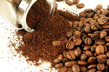 Wall Mural - dark roasted coffee beans and ground coffee powder closeup on white background 