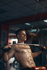 Muscular model young man exercising in gym. Portrait of sporty strong muscle. Fitness trainer. Sport workout bodybuilding motivation concept. Sexy naked torso, six pack abs. Male flexing his muscles.