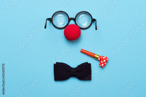 Cuadros en Lienzo Funny glasses, red clown nose and tie lie on a colored background, like a face