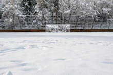 Snow Covered Soccer Field And Goal Net, With Forest Background