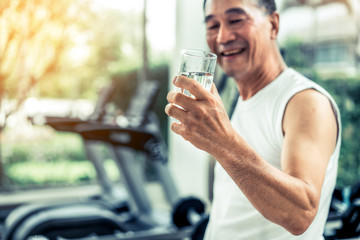 Wall Mural - Senior man drink mineral water in gym fitness center after exercise. Elderly healthy lifestyle.