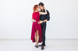© satura_ - Social dance, bachata, kizomba, salsa, tango concept - Woman dressed in red dress and man in a black costume over white background with copy space