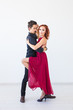 © satura_ - Social dance, bachata, kizomba, salsa, tango concept - Woman dressed in red dress and man in a black costume over white background