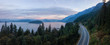 Aerial panoramic view of the scenic highway surounded by the Beautiful Canadian Mountain Landscape during a summer sunrise. Taken in Sunset Beach, North of Vancouver, British Columbia, Canada.