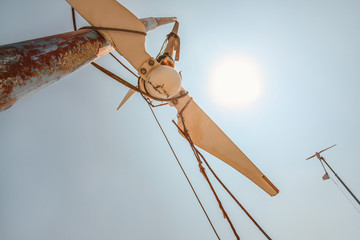 Wall Mural - looking up small broken wind turbine, strong midday sun shining in back