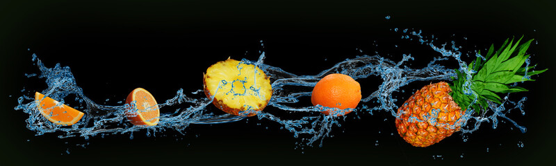 fruit - orange and pineapple in water on an isolated green and black background