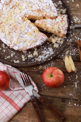 Wall Mural - Sweet homemade apple pie on a plate with fresh apples and cinnamon sticks on a rustic wooden table