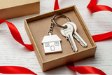 Fototapeta  - Keychain house and keys with red ribbon and gift box on white wooden background.
