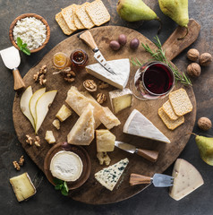Wall Mural - Cheese platter with different cheeses, fruits, nuts and wine on stone background. Top view. Tasty cheese starter.