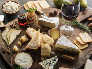 Wall Mural - Cheese platter with different cheeses, fruits, nuts and wine on stone background. Top view. Tasty cheese starter.