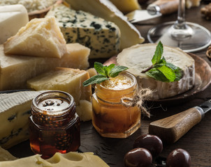 Wall Mural - Cheese platter with organic cheeses, fruits, olives and jam on wooden background. Tasty cheese starter.
