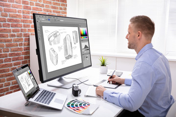 Designer Drawing Suitcase On Computer Using Graphic Tablet