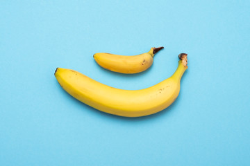 Small banana compare size with banana on blue background. size penis concept