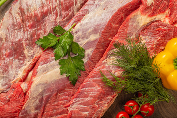 Wall Mural - Raw beef on a wooden background with spices and vegetables.