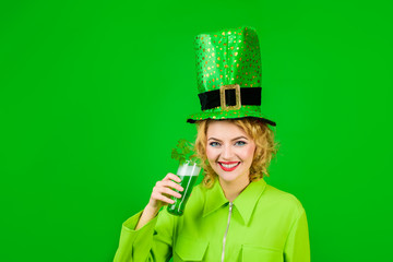 Woman celebrating St. Patrick's Day with beer. Beautiful girl in green leprechaun hat drinking green beer. St. Patrick's Day celebration. Patrick Day pub party. Saint Patrick's day or october festival