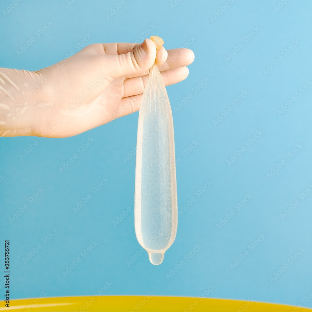 full condom Hand in medical gloves holding condom full of water Stock Photo | Adobe Stock