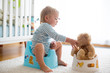 Cute toddler boy, potty training, playing with his teddy bear