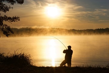 Wall Mural - Silhouette of angler during misty sunrise