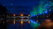 Evesham River Avon night time shot of coloured floodlight on trees being reflected in a still water with Workman Bridge, moon and stars.