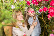 Mother And Daughter carying plants, gardening In greenhouse