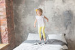 Happy child girl having fun jumping on a bed