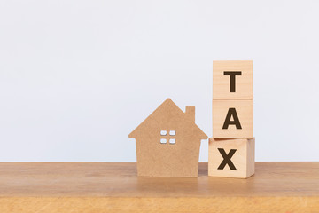 Wall Mural - House model and wooden cubes with alphabet TAX on wooden table. Home taxes decrease concept