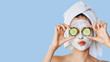 Leinwandbild Motiv Beautiful young woman with facial mask on her face holding slices of cucumber. Skin care and treatment, spa, natural beauty and cosmetology concept.