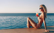 © Mykhailovskyi - girl in an expensive swimsuit with a cocktail in her hands spends her vacation near the pool at the resort