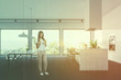 © ImageFlow - Side view of white kitchen, bar and table, woman