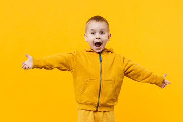 Little cute kid boy 3-4 years old wearing yellow clothes isolated on bright orange wall background, children studio portrait. People sincere emotions, childhood lifestyle concept. Mock up copy space.