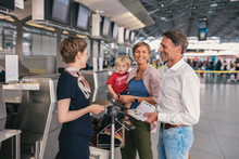 Happy Family With Airline Employee At The Airport Check-in