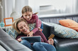 © Westend61 - Happy mother and daughter shopping online on couch at home