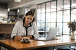 © Westend61 - Young businesswoman in a cafe writing on paper and working with laptop on wooden table