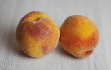 Two peaches on the light wooden background