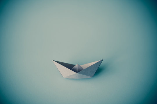 gray tone paper boat on clean background with copy space, journey and obstacle concept