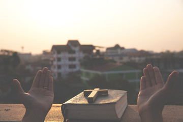 Women pray to God with the Bible and the cross  with morning sunrise. Woman Pray for god blessing to wishing have a better life. Christian life crisis prayer to god.