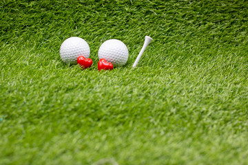 Two golf ball are on green grass with love and tee 