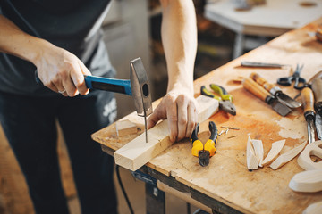 Wall Mural - A man carves a tree. The carpenter works with hammer in a studio. An engineer provides a tree shape