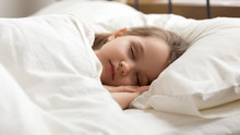 Calm Kid Girl Sleeping In Bed Covered With Warm Duvet