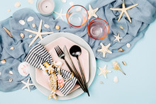 Tableware And Sea Decorations For Serving A Festive Table. Plates, Wine Glasses And Cutlery On Blue Background. Summer Concept. Flat Lay, Top View