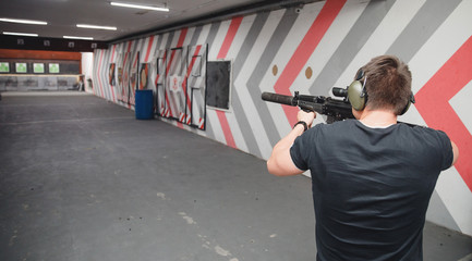 Canvas Print - Shooting training. Man shoots from aim gun in paper target