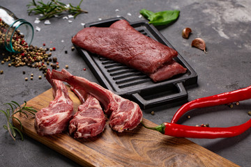 Wall Mural - Set of Raw uncooked black angus beef tomahawk steaks on bones and veal tenderloin served with chilli and peppercorns. Rustic style.