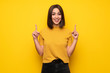 Young woman over yellow wall pointing with the index finger a great idea