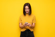 © luismolinero - Young woman over yellow wall sending a message with the mobile