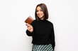 © luismolinero - Young woman over white wall holding a wallet