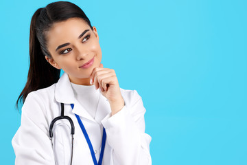 Charming young woman doctor with stethoscope over blue background.