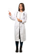 © luismolinero - A full-length shot of a Young doctor woman pointing finger to the side over isolated white background