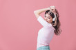 © Rychko Yevhen - beautiful blonde woman in pink t-shirt and white headphones listens to music on pink background. summer studio photoshoot