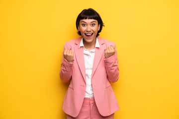 Modern woman with pink business suit celebrating a victory in winner position