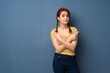 © luismolinero - Young redhead woman over blue background pointing to the laterals having doubts